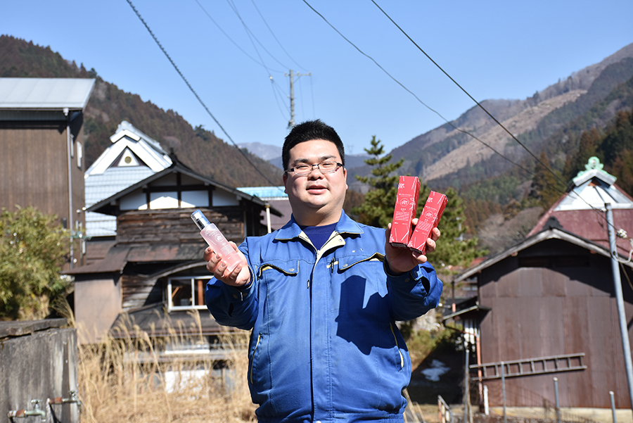 奥永源寺の景色を背景に化粧品をもつ前川さん