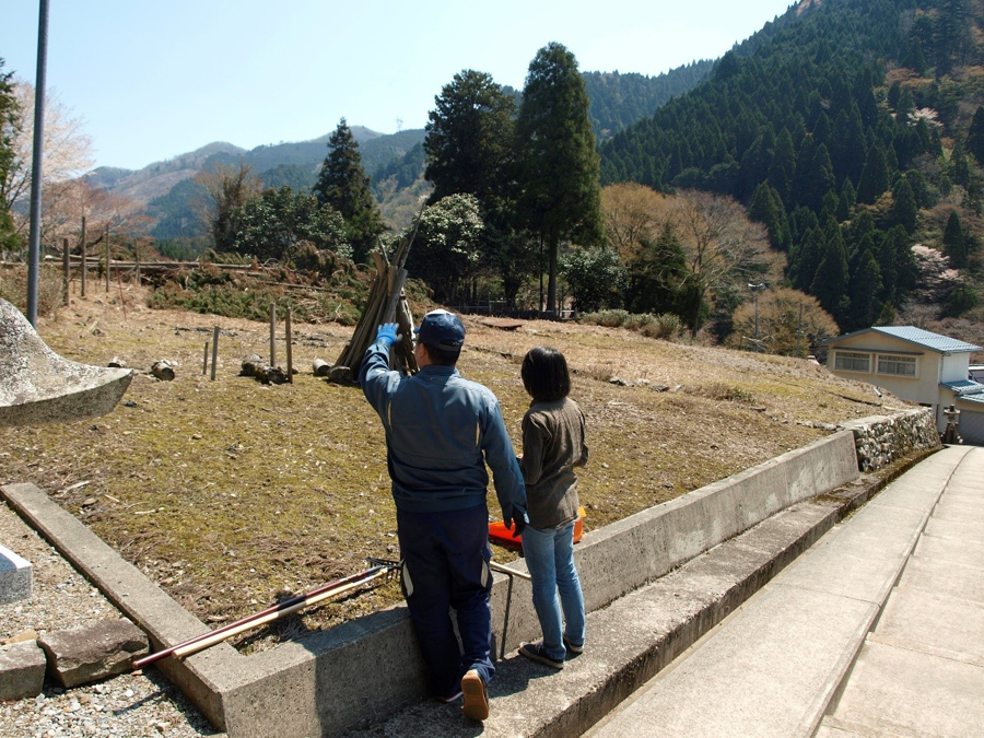 耕作放棄地の前に立ち眺める前川さんら